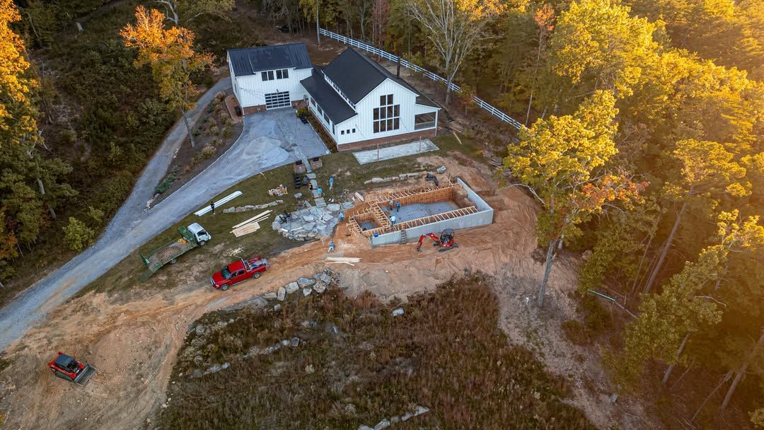 Aerial view: A house under construction on a hillside. Red truck and construction equipment present.
