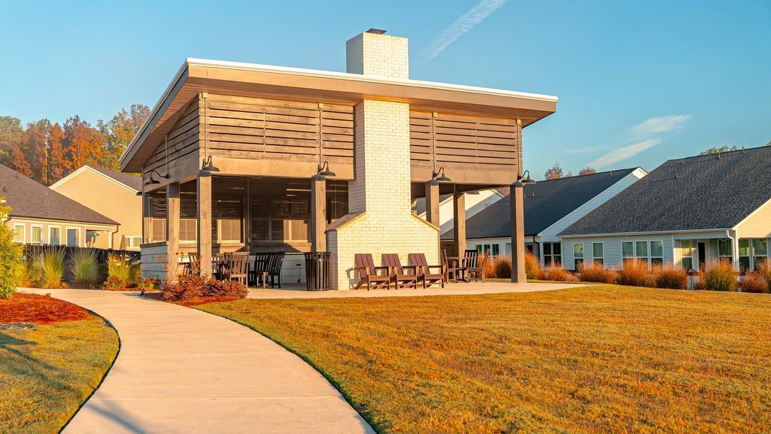 Outdoor covered patio with fireplace and seating, on a grassy area, pathway.