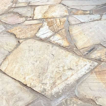 Irregular flagstone patio in shades of tan and gray with concrete joints.