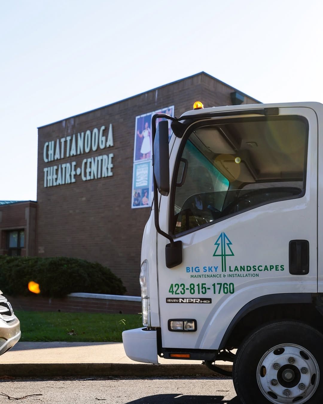 Truck parked in front of the Chattanooga Theatre Centre. White truck with Big Sky Landscaping logo, phone number.