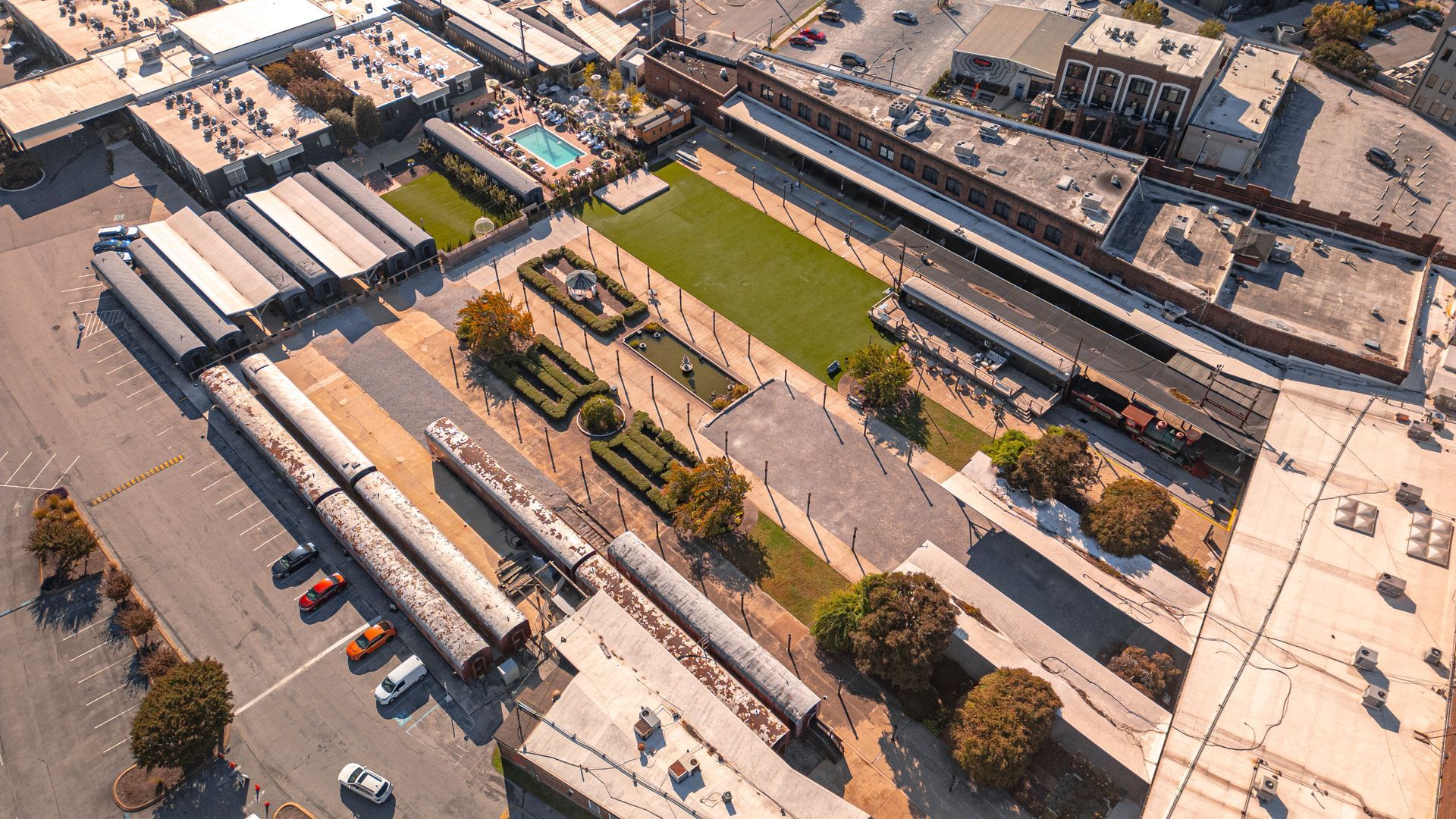 Aerial view of a long, open-air marketplace with several train cars and green space.
