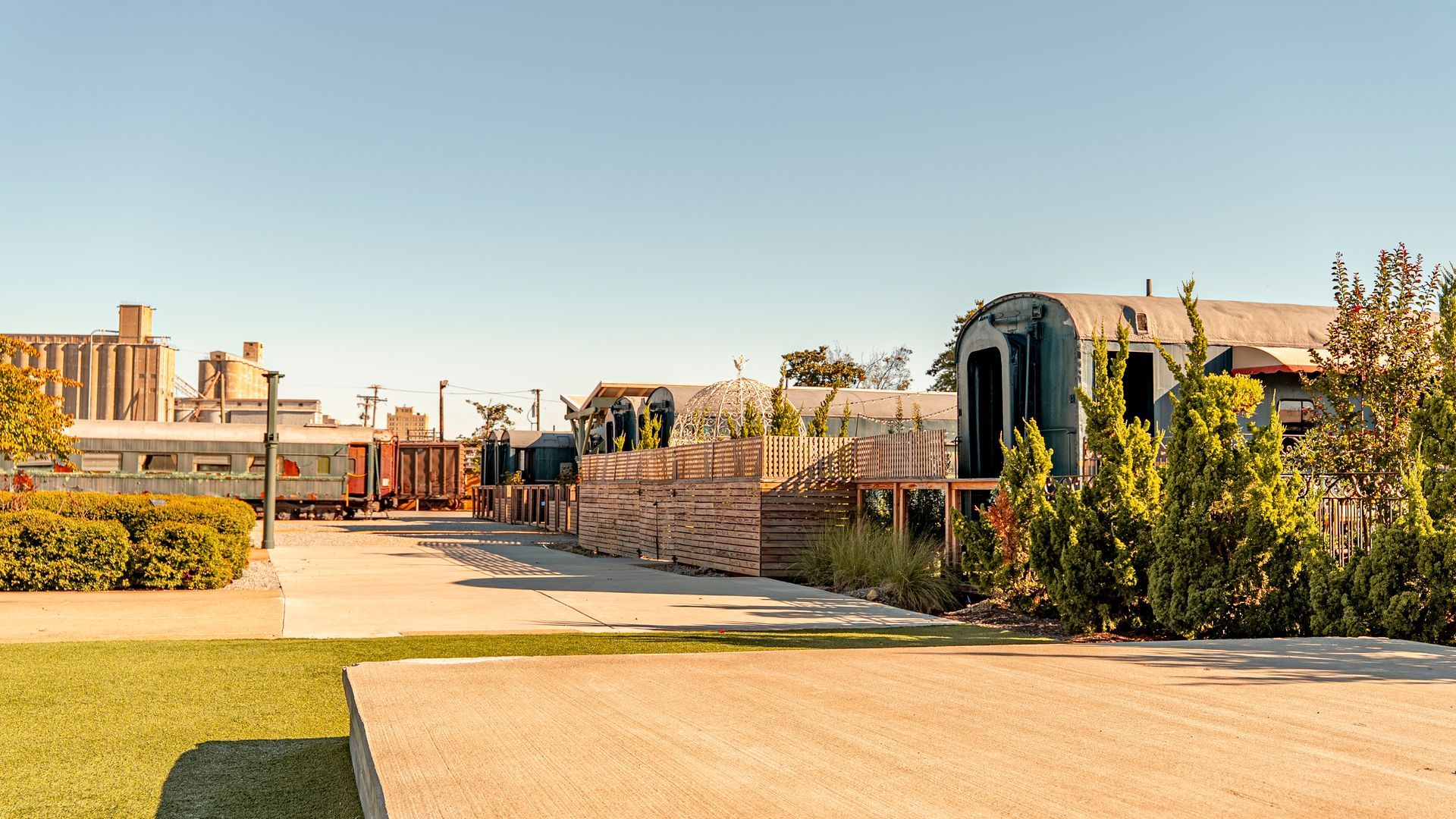 Train cars repurposed into buildings with wooden structures and vegetation.