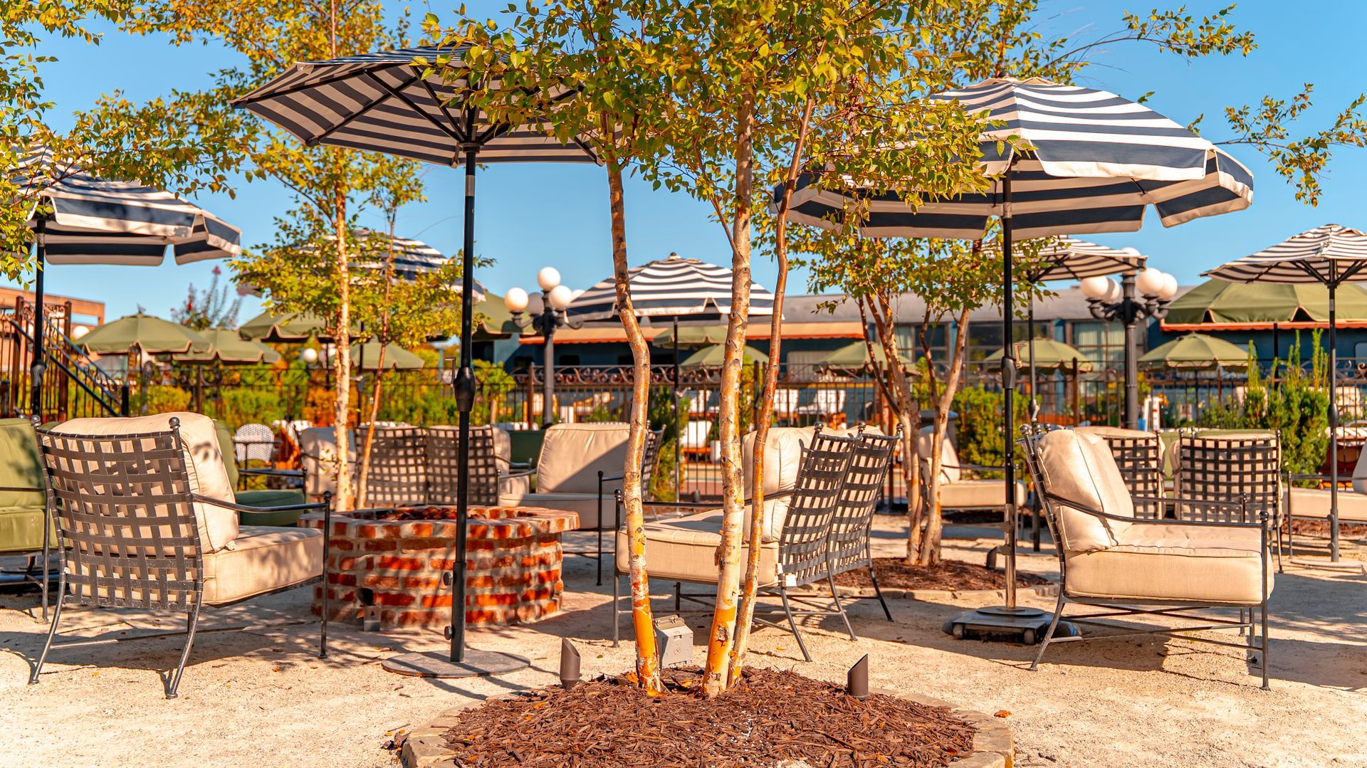 Outdoor seating area with striped umbrellas, chairs, and a fire pit.