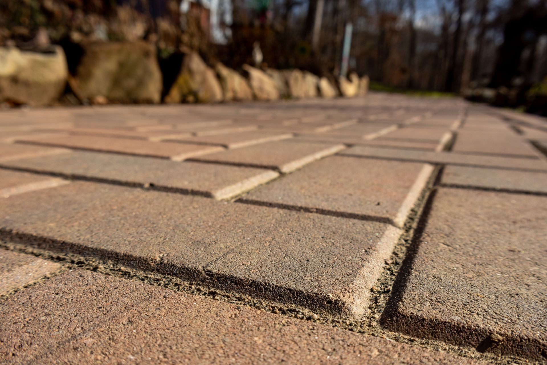 Close-up of brown paving stones laid in a herringbone pattern, outdoors.