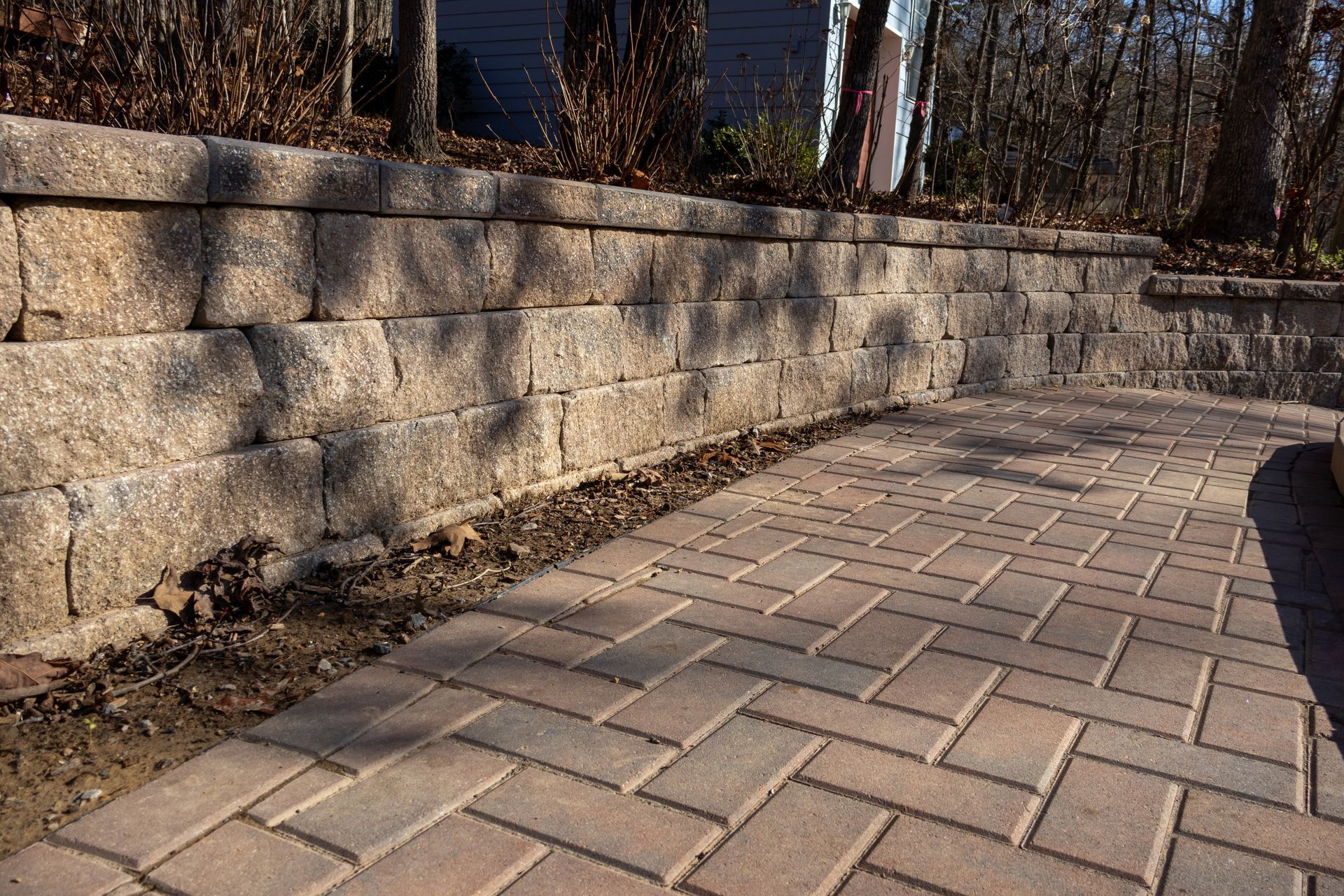 Brick patio with a retaining wall made of stacked stone blocks.