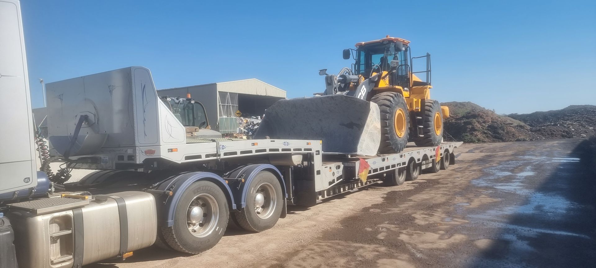A semi truck is carrying a tractor on a flatbed trailer — Ballarat Supatilt in Delacombe, VIC