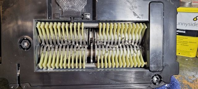 Close-up of a yellow and black mechanical roller brush inside a vacuum cleaner housing