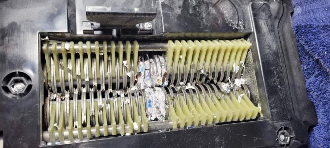 Close-up of a damaged electrical connector with bent metal pins and yellow residue inside a black housing