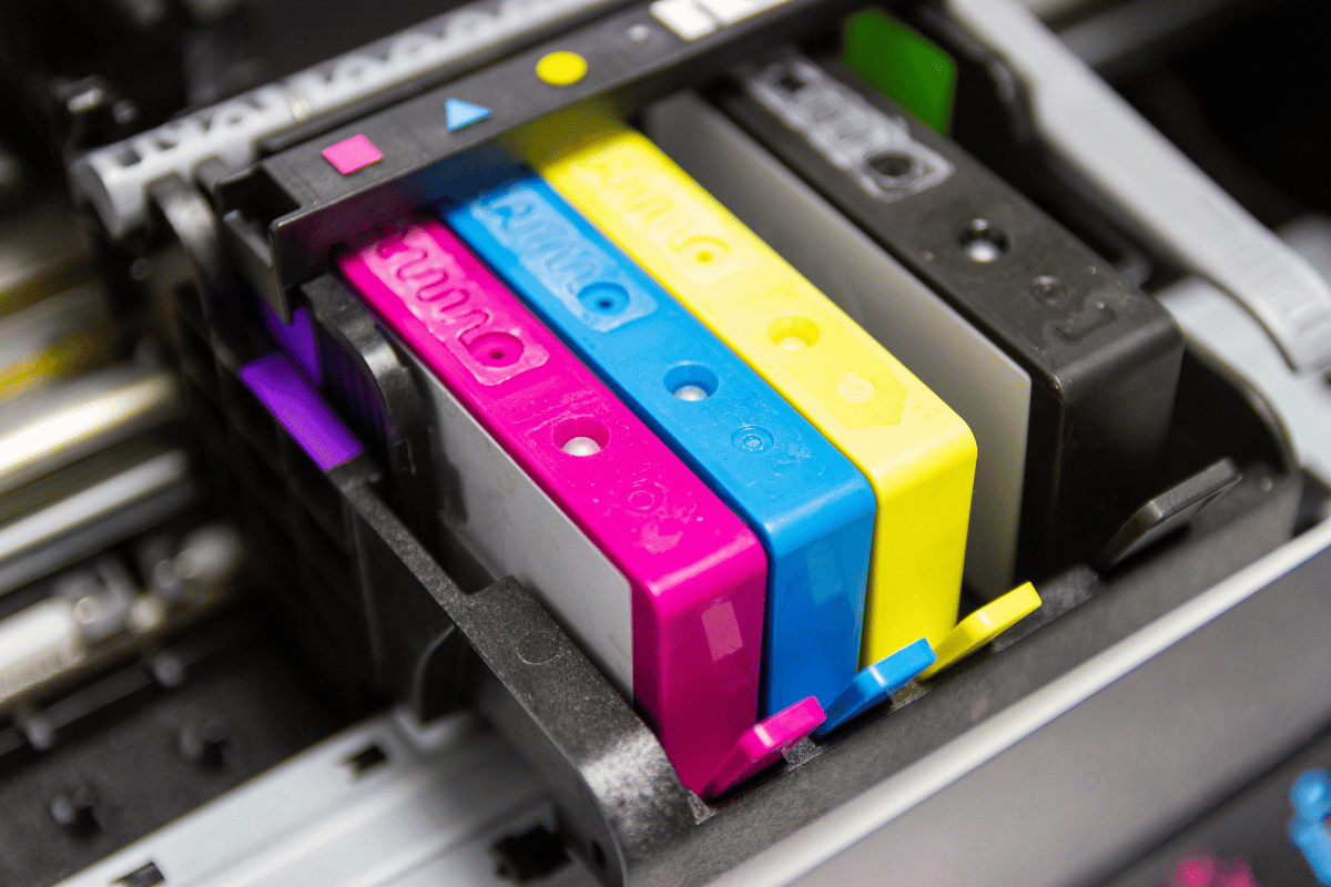 Color ink cartridges in a printer, showing magenta, cyan, yellow, and black tanks.