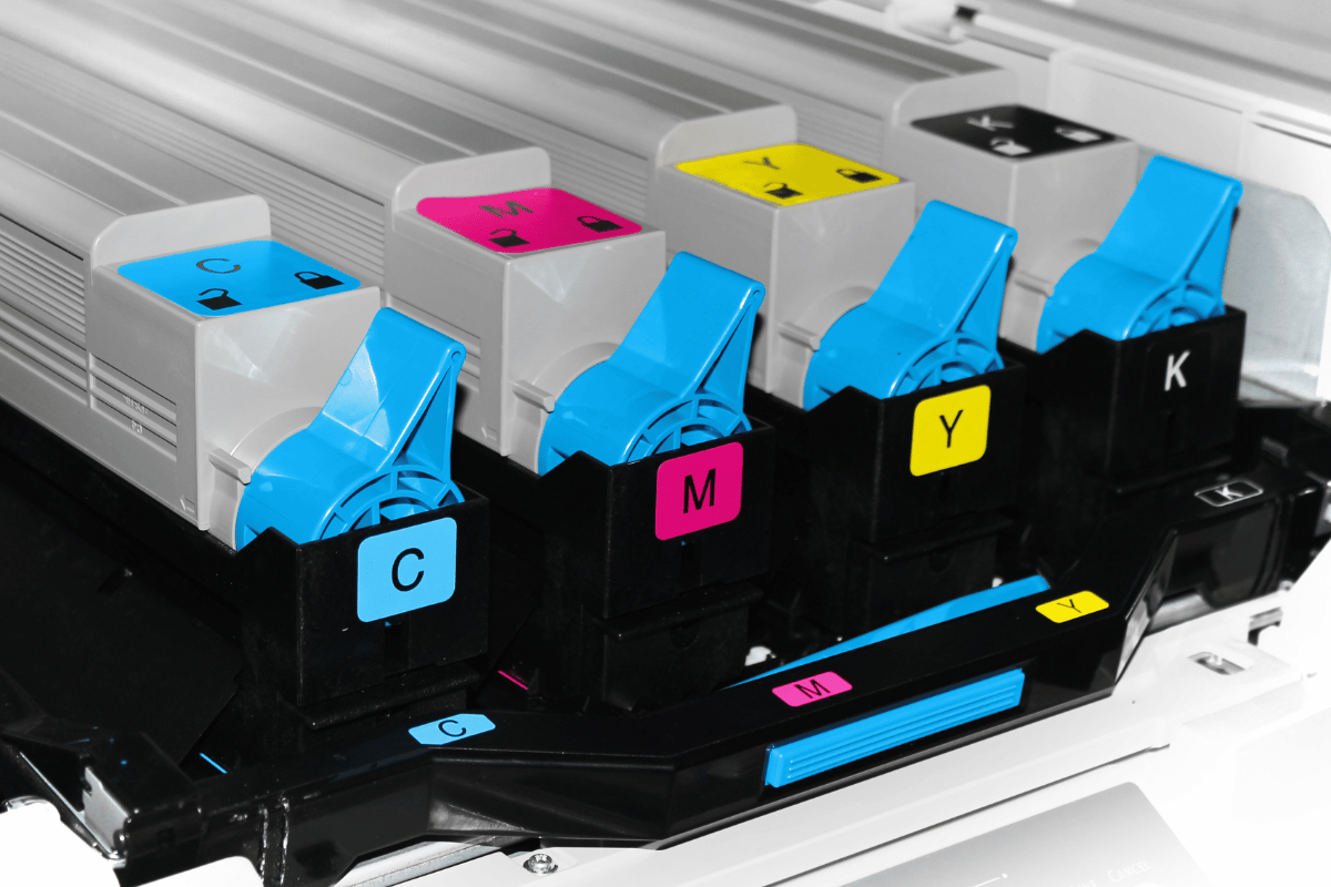 Color-coded printer ink cartridges labeled C, M, Y, and K in a printer carriage