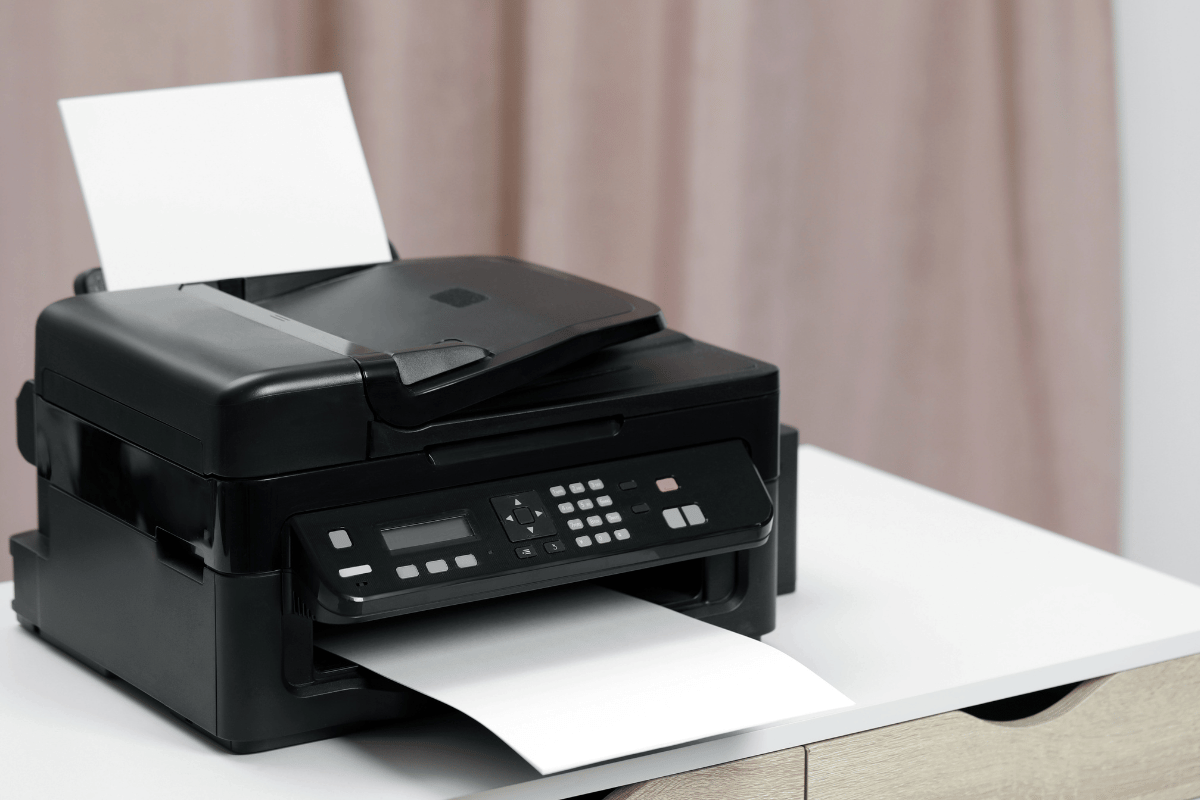 Black all-in-one printer on a desk printing a sheet of paper