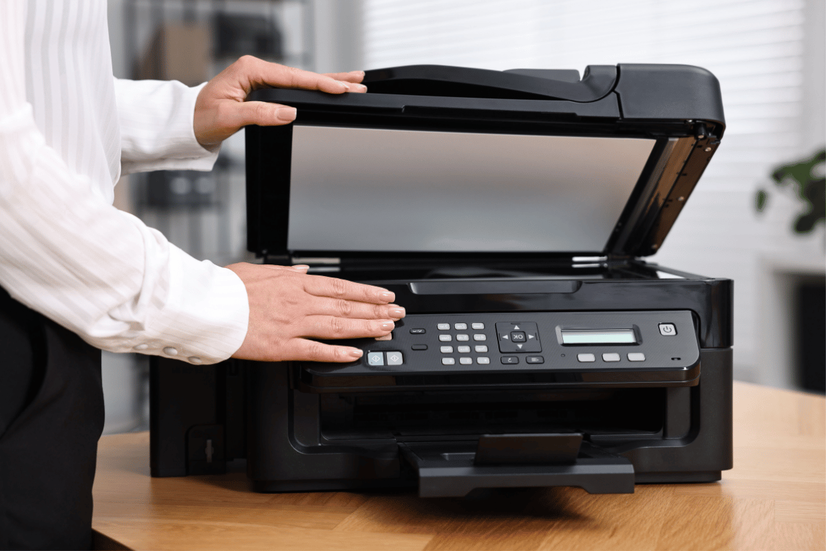 Large-format printer in a bright office, with paper rolls and colorful print materials nearby
