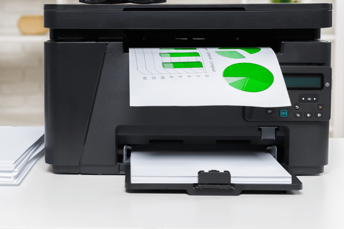Black desktop printer printing a page with green charts and graphs