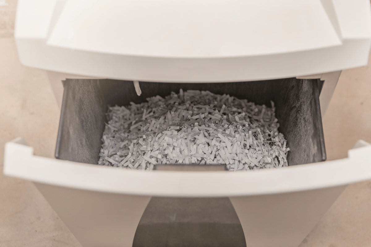 Open paper shredder drawer filled with shredded paper
