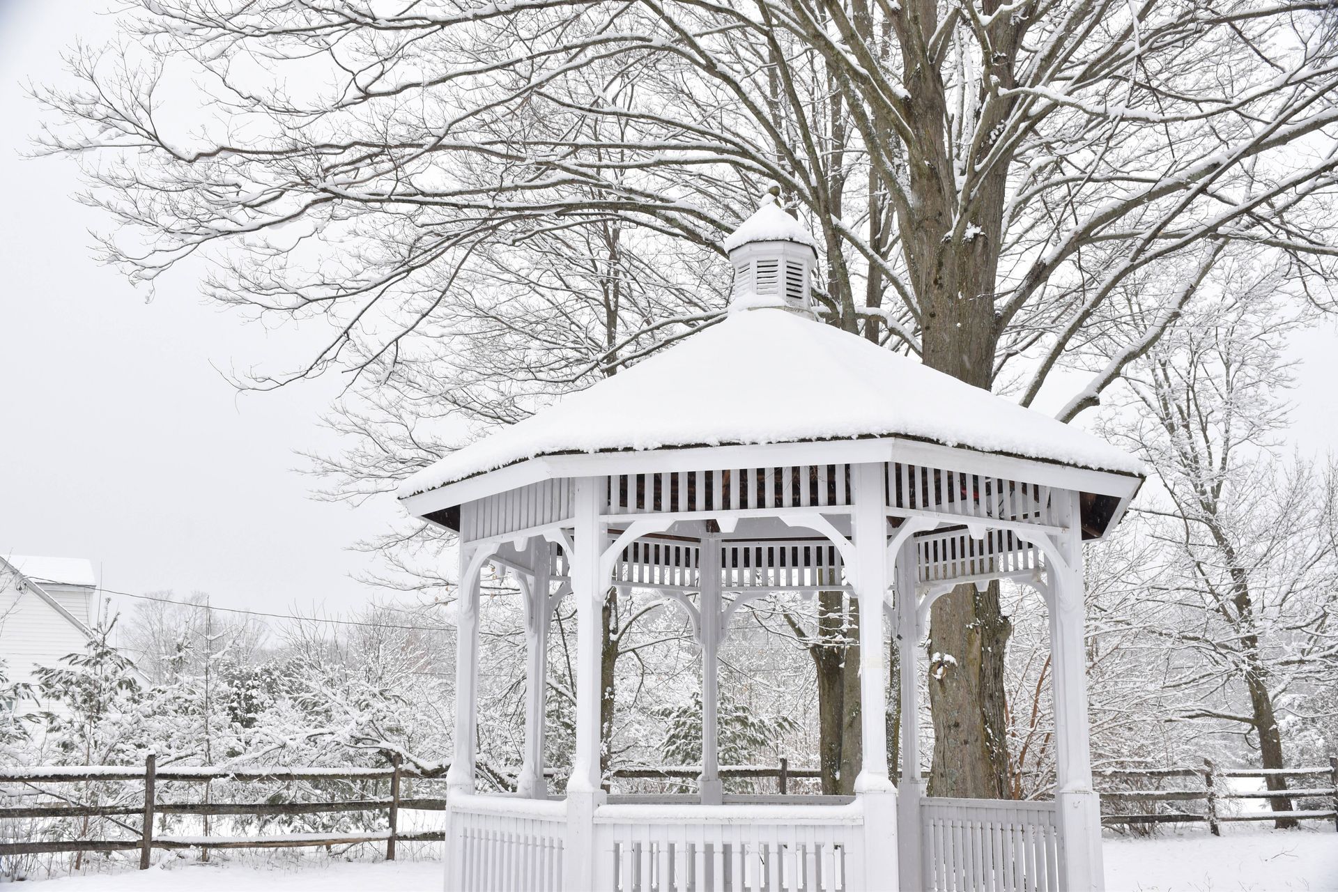 A stunning winter scene with a vinyl gazebo covered in glistening snow in a residential neighborhood at SummerHouse Outdoor Structures near Central Pennsylvania