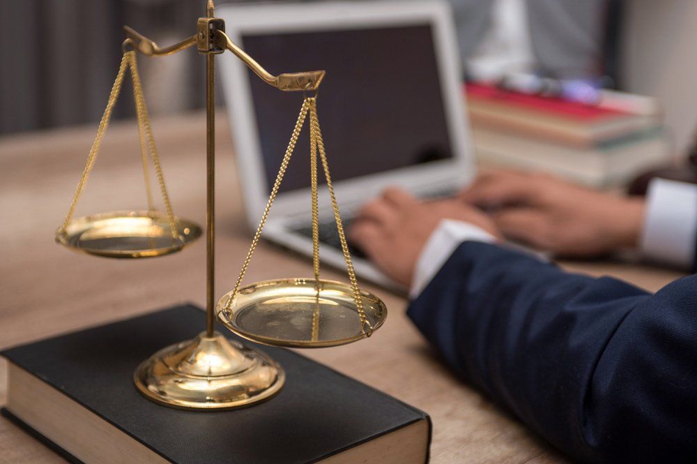 Law Scale Beside Man Using A Laptop — Gibsonville, NC — Walker & Bullard PA