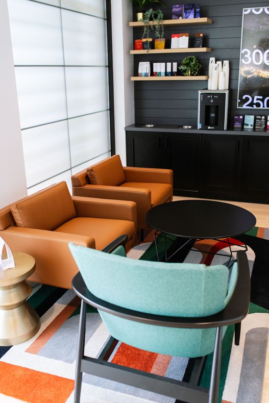 a waiting room with chairs , a table and a coffee maker .