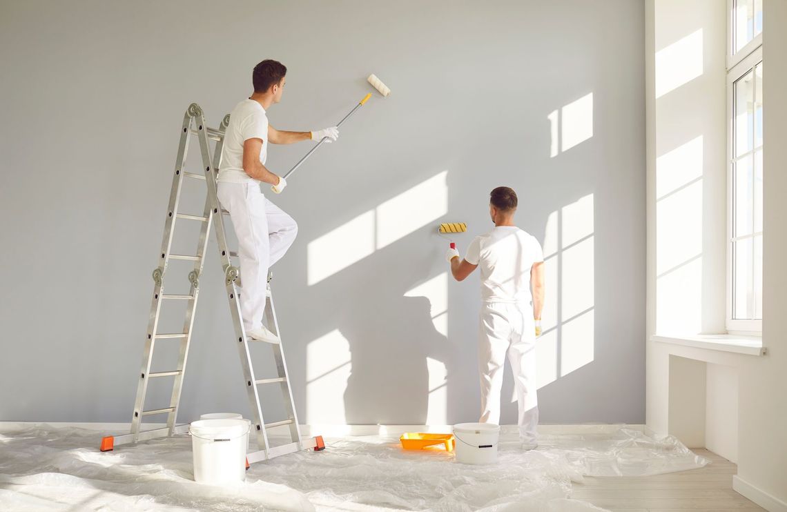 A man and a woman are cleaning a living room.