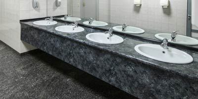 A row of sinks in a public restroom with mirrors.
