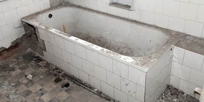 An empty bathtub in a bathroom with white tiles.