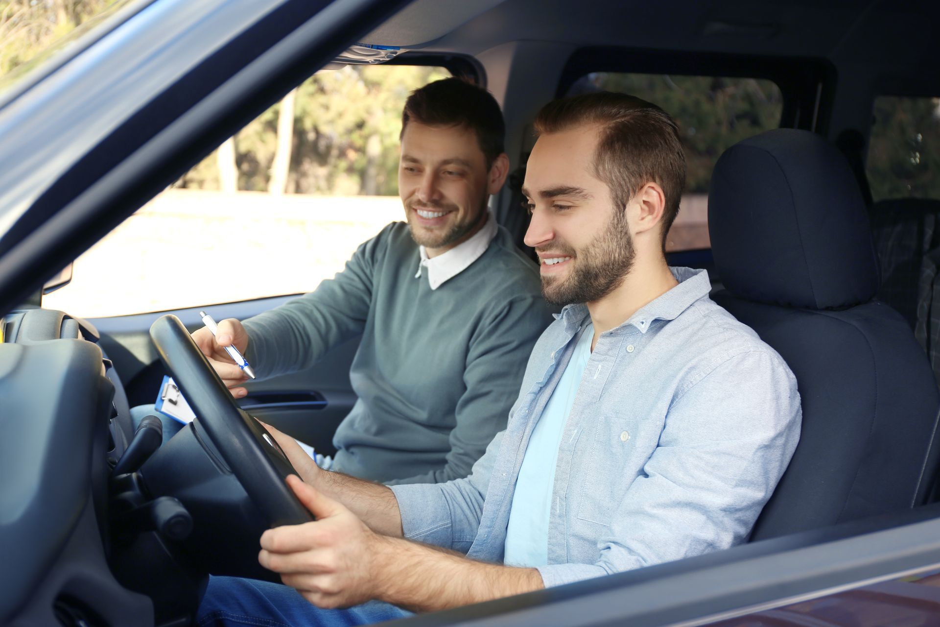 Driver and instructor in car, smiling. 