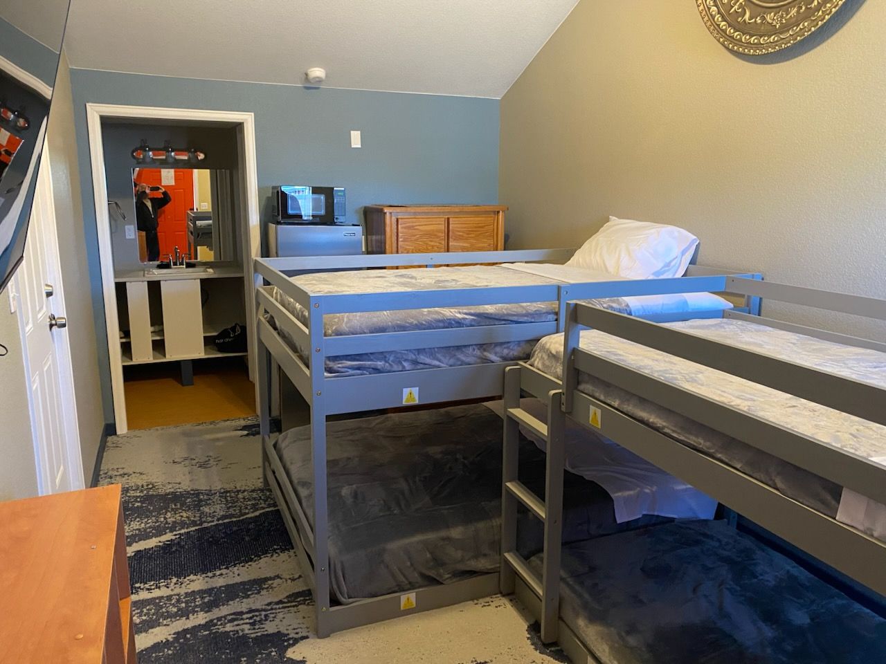 Cozy hotel room with a fireplace, bunk beds, and a bed facing a mountain view through large windows.