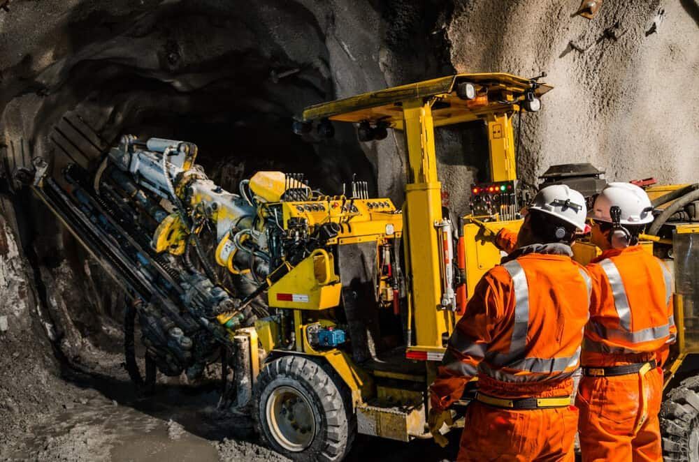 A Group of Men Are Standing in Front of a Machine in a Tunnel — Calibre Resourcing Solutions in Cairns, QLD