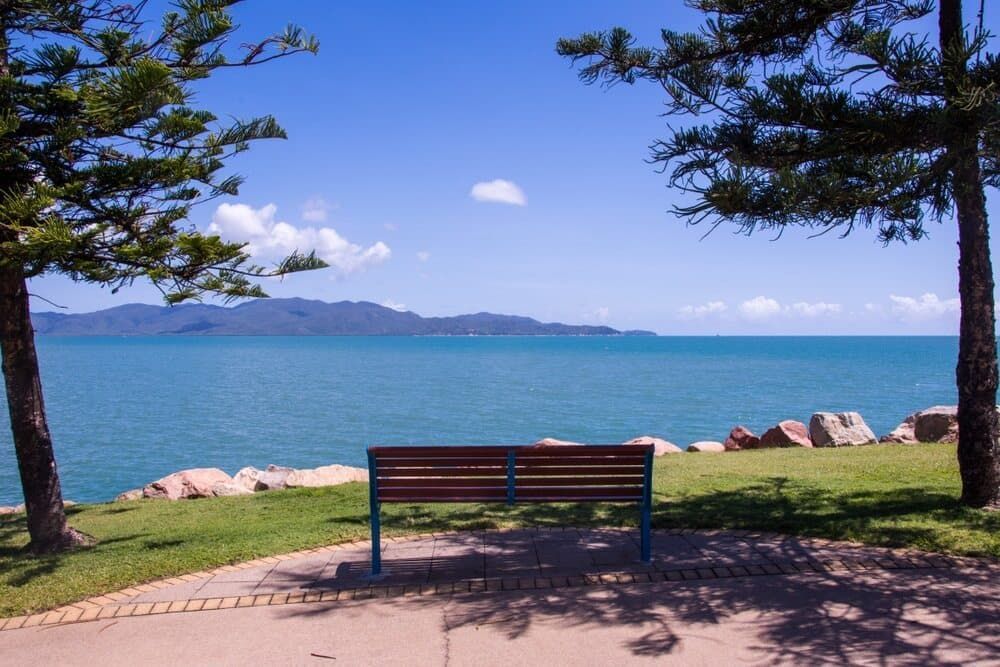 A Wooden Bench Sits in Front of a Body of Water — Calibre Resourcing Solutions in Townsville, QLD