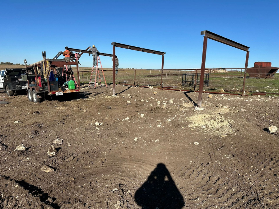 Destroyed metal structures in a barren field under a clear blue sky.