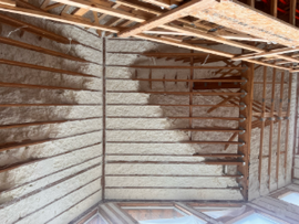 Dusty unfinished room with exposed wooden framing and slatted walls under construction