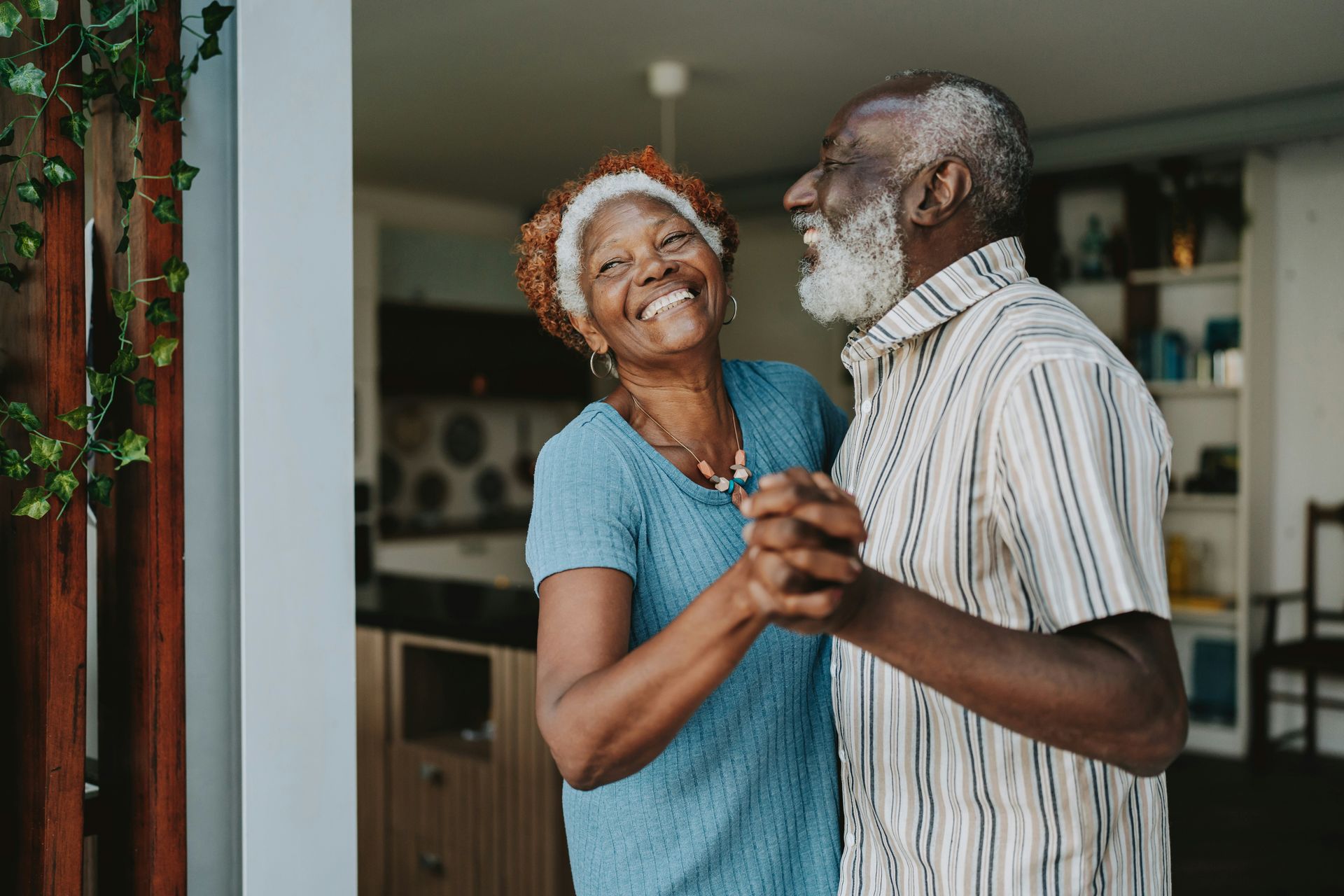Two people smiling and dancing together in a cozy room.