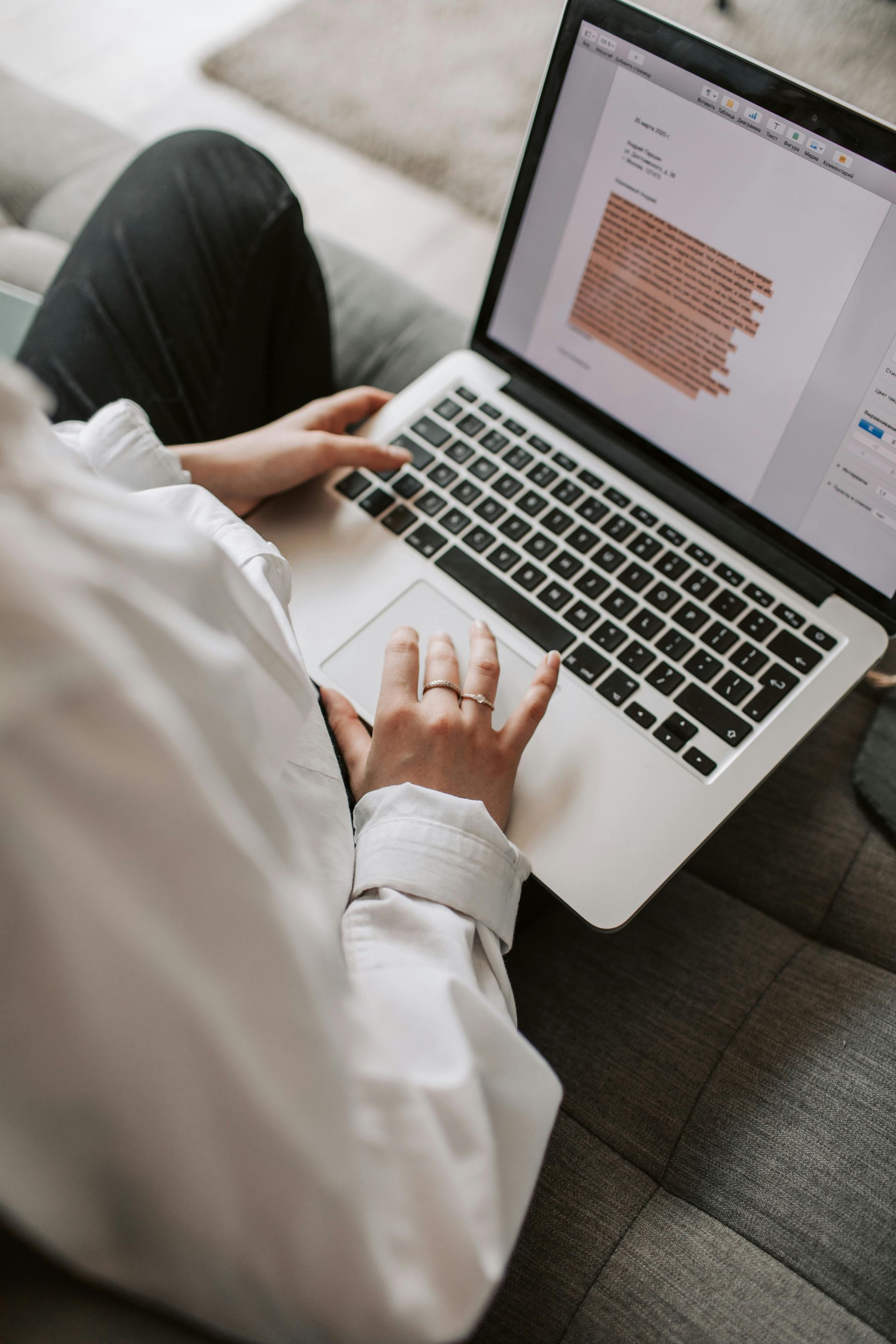 Person typing on a laptop with a document open on a couch