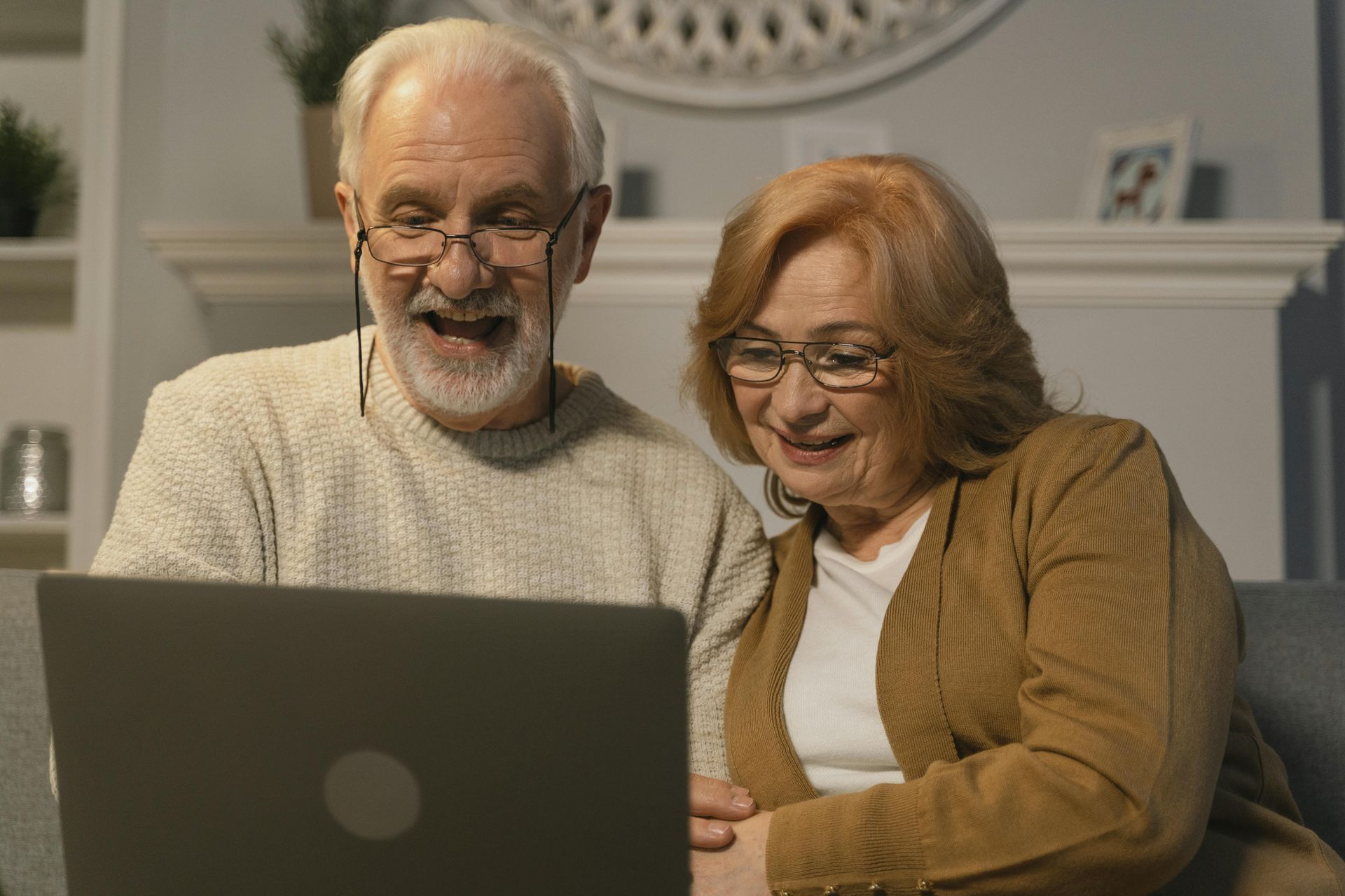 Smiling couple using a laptop together in a cozy living room