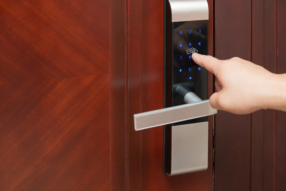 A person’s finger touches a glowing touchscreen keypad on a modern smart door lock mounted on a wooden door.