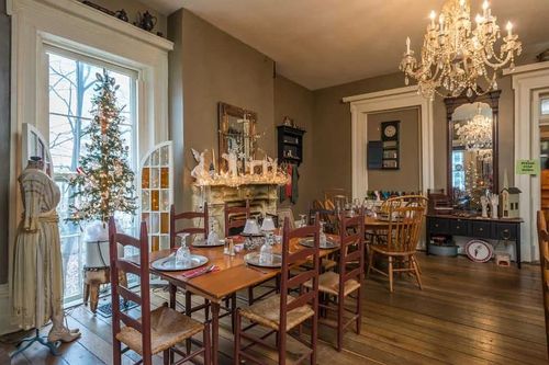 A dining room with a table and chairs and a christmas tree.