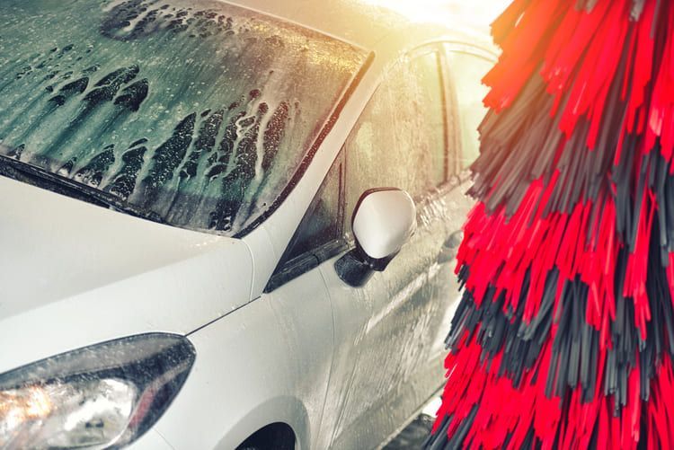 A white car is being washed in an automatic car wash.