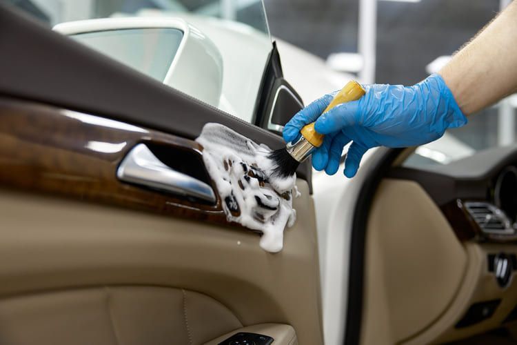 A professional cleaning the interior of a car with a brush.