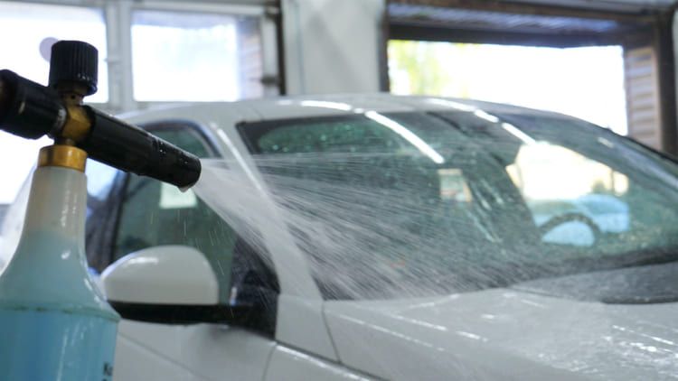 Car shampoo spraying a car for cleaning purposes.