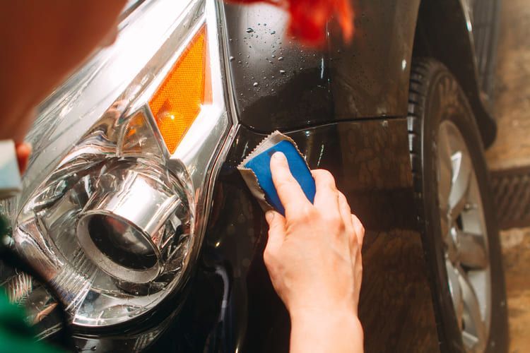 A professional is polishing a car with a clay bar.