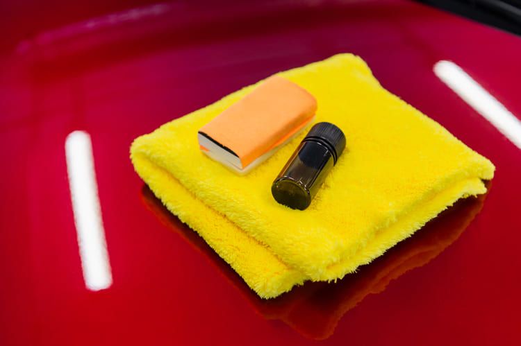 Ceramic coating products placed on top of a shiny red car