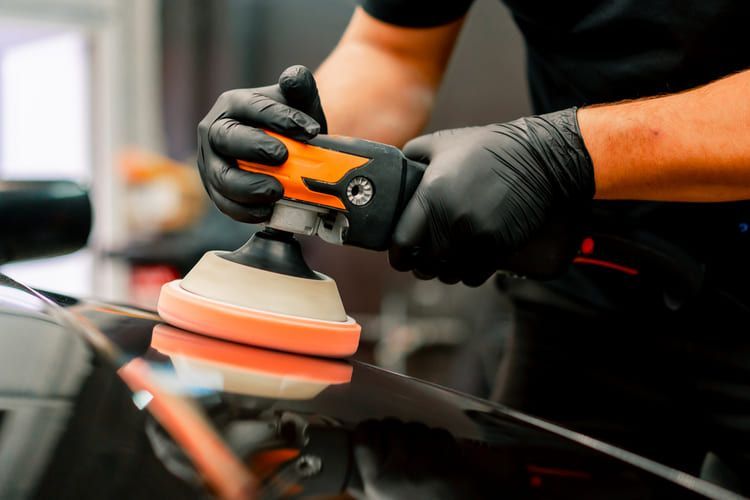 A man is polishing a car with a machine.