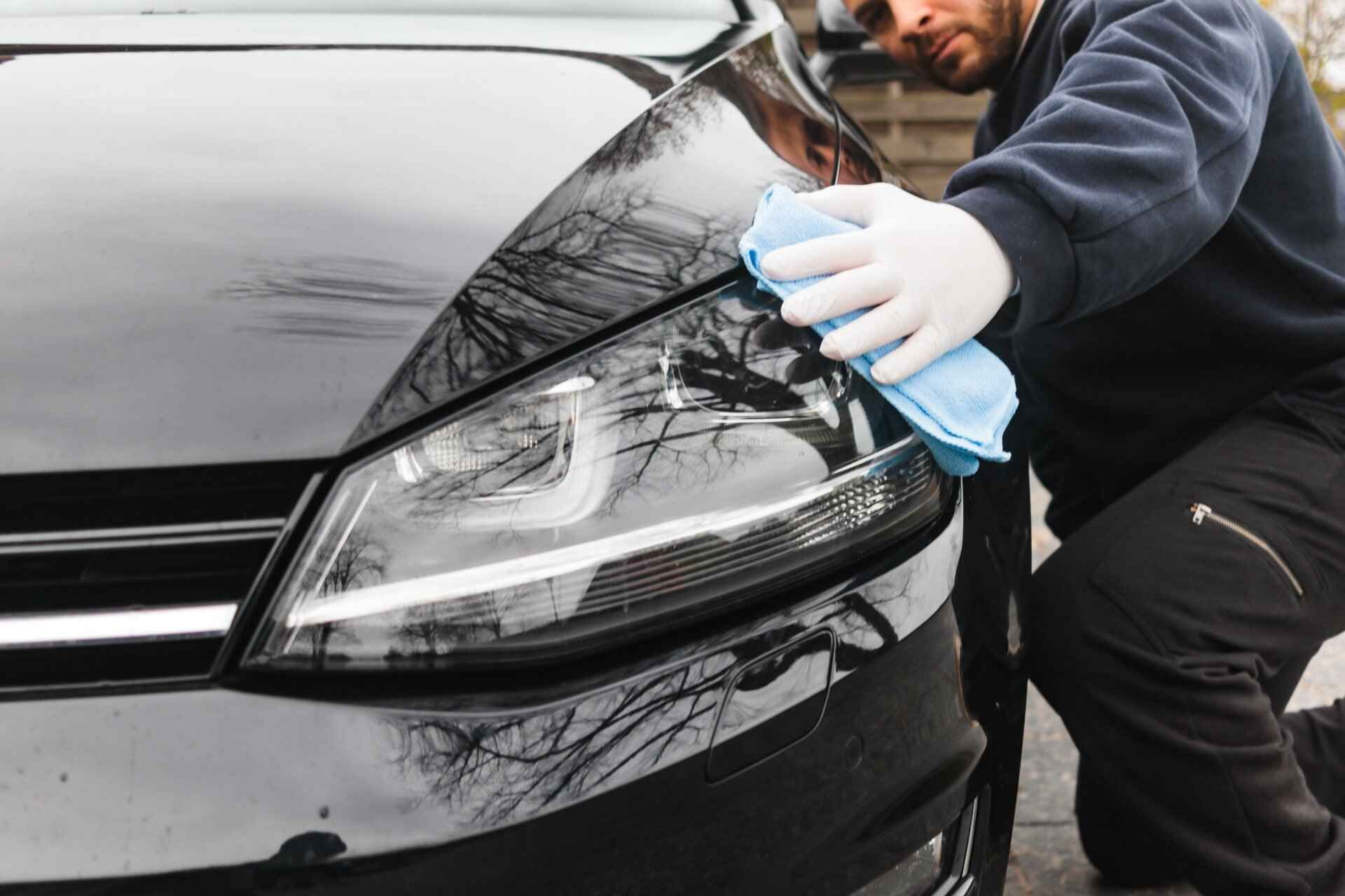Picture showcasing a professional worker providing an exterior car valet.