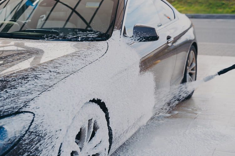 A person is washing a car with a high-pressure washer.
