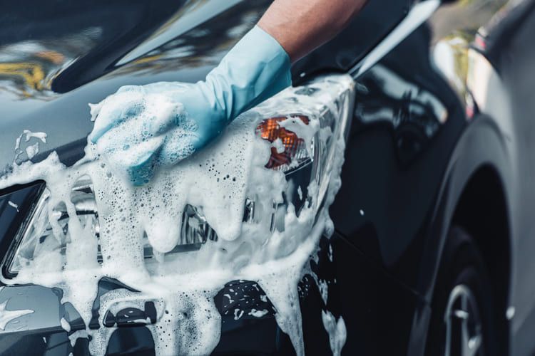 A person is washing a car with soap and water.