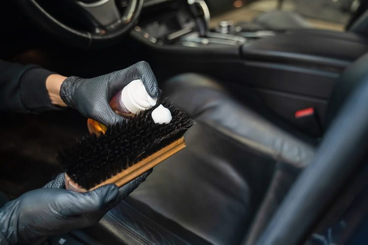 A person is cleaning the interior of a car with a brush.