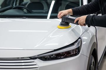 Picture showcasing a professional worker providing car detailing service.