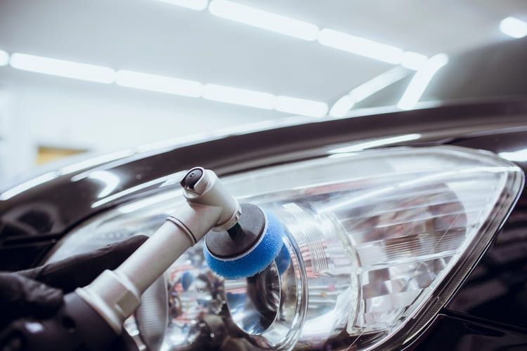 A close up of a person polishing a car headlight.