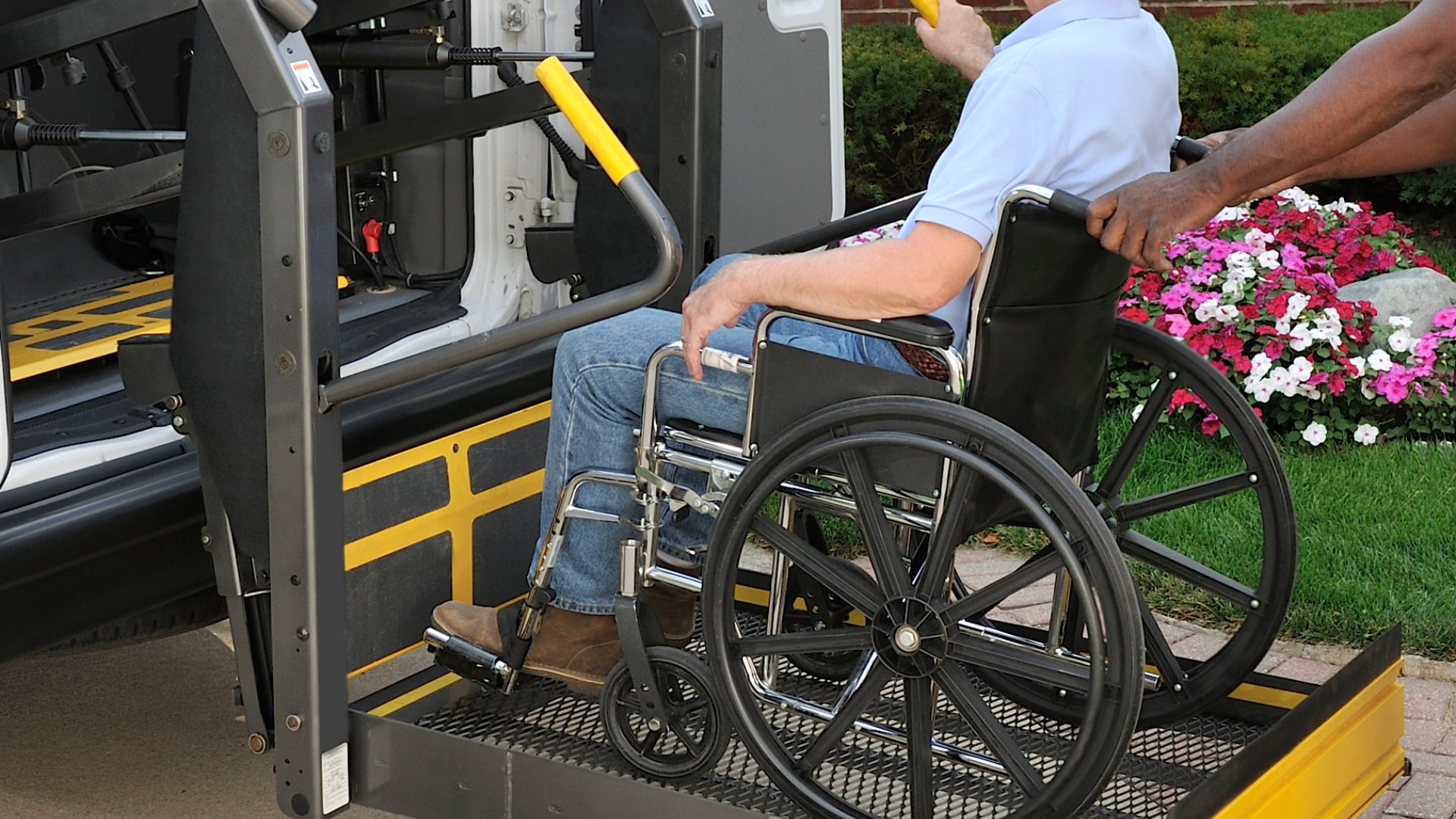 Person in a wheelchair boarding a bus using the lift ramp at a curbside stop