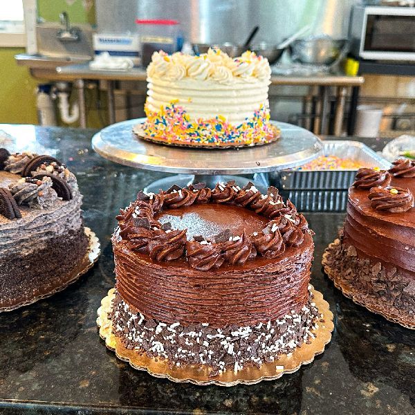 Several cakes on display at a bakery. Chocolate, vanilla, and sprinkles are visible.