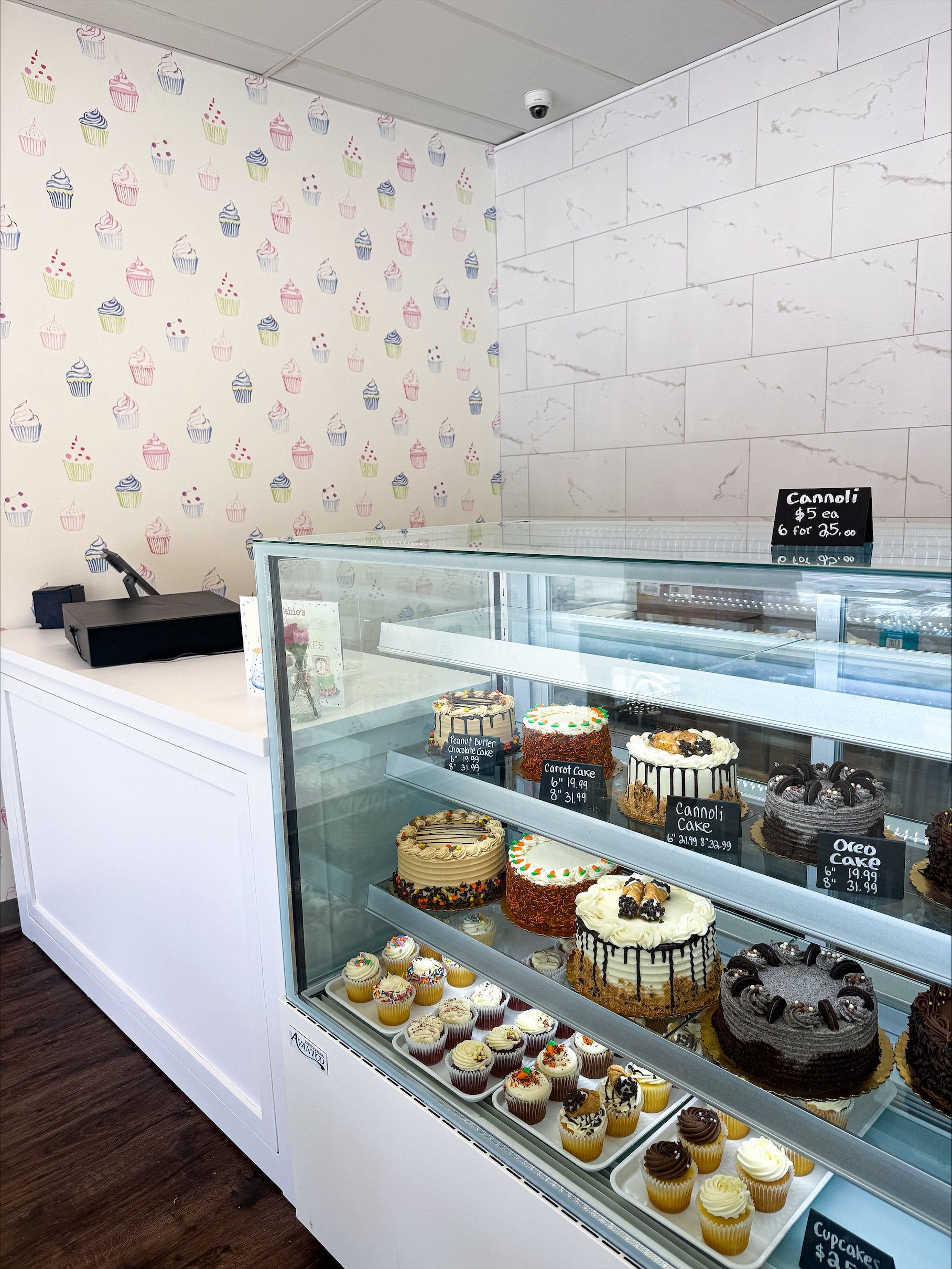 Bakery display case with assorted cakes and pastries in a bright shop corner